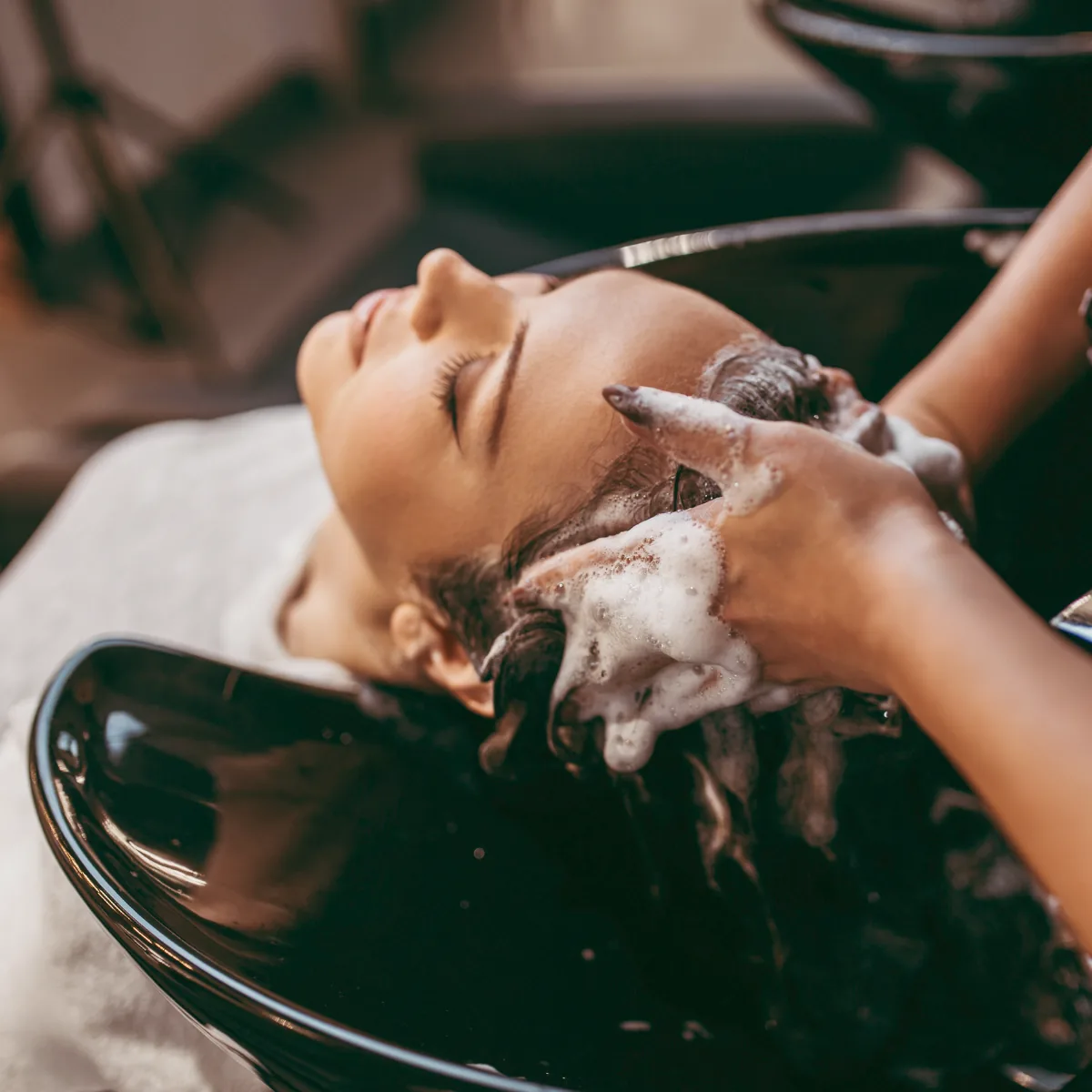 A client at the shampoo bowl having her hair lathered